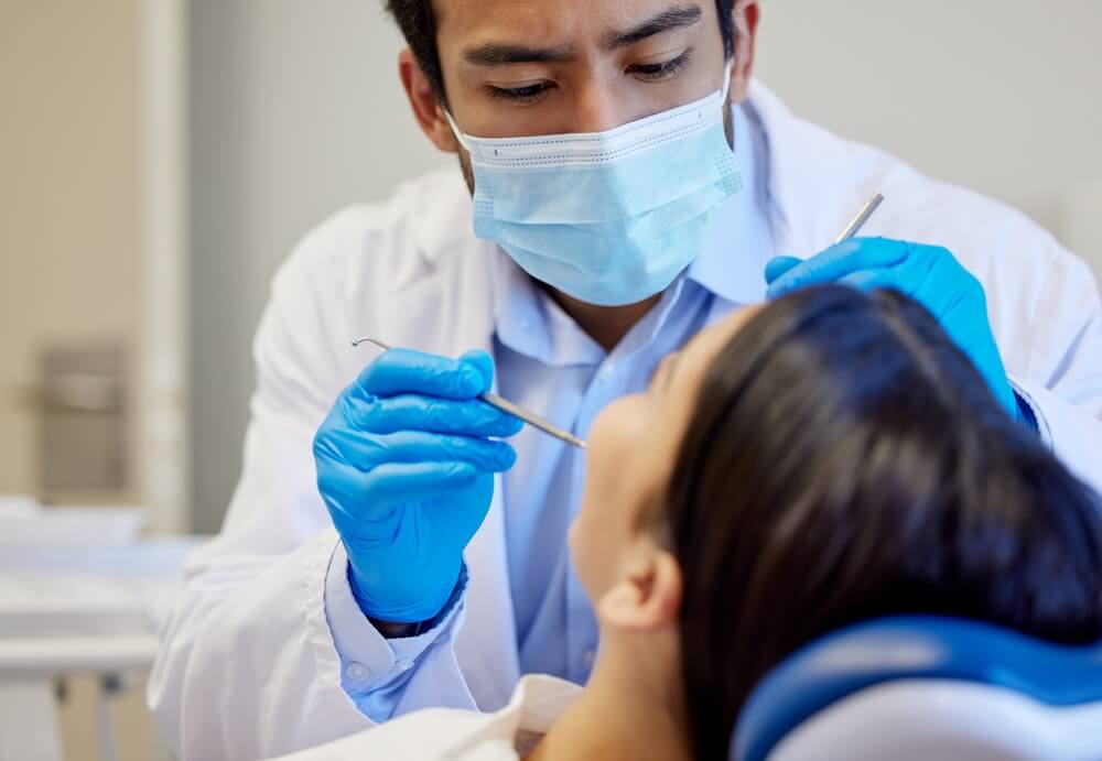 Cosmetic dentist at Perfect Smile Spa examining a chipped tooth during emergency dental consultation